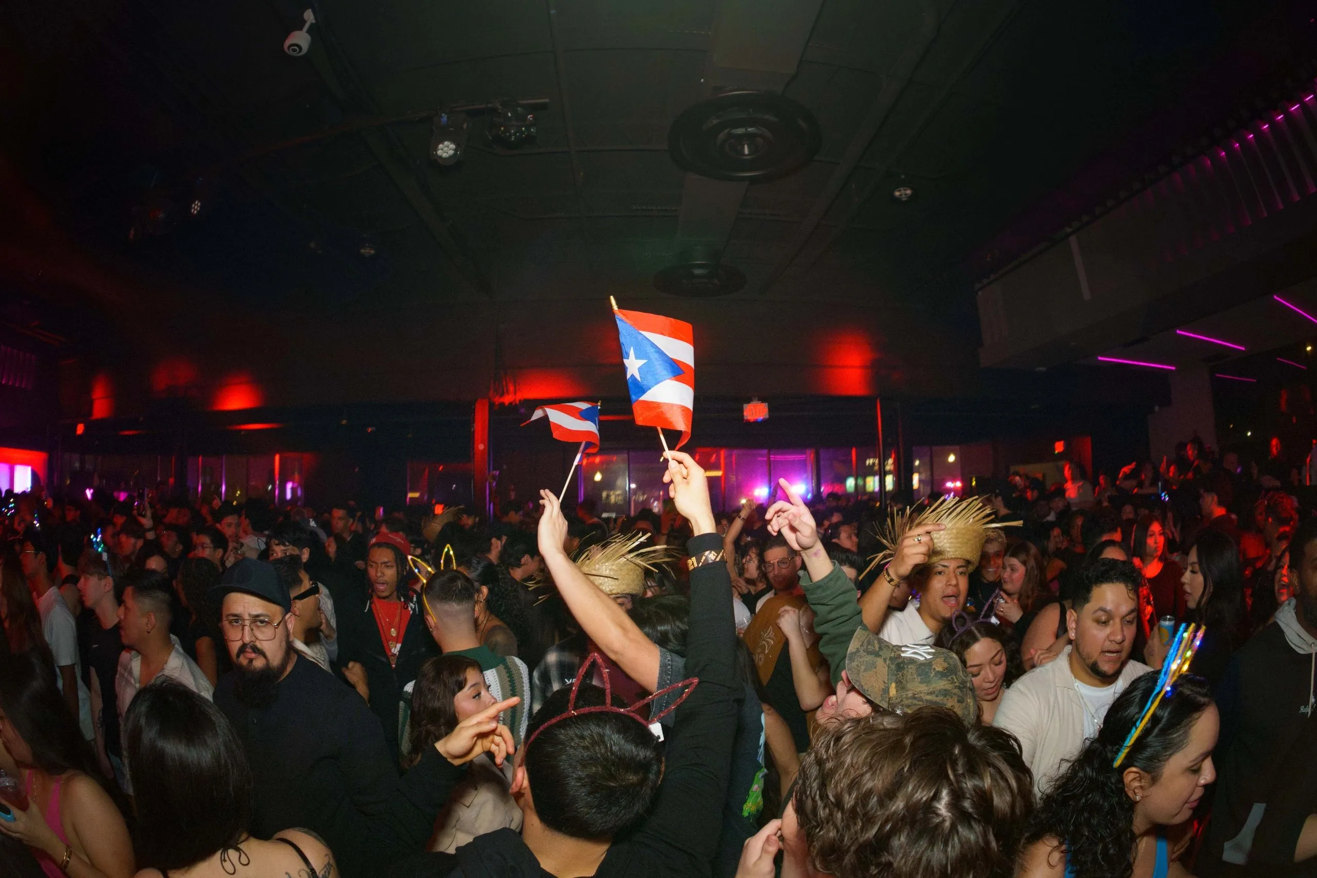 A Puerto Rican flag held open above a packed floor.