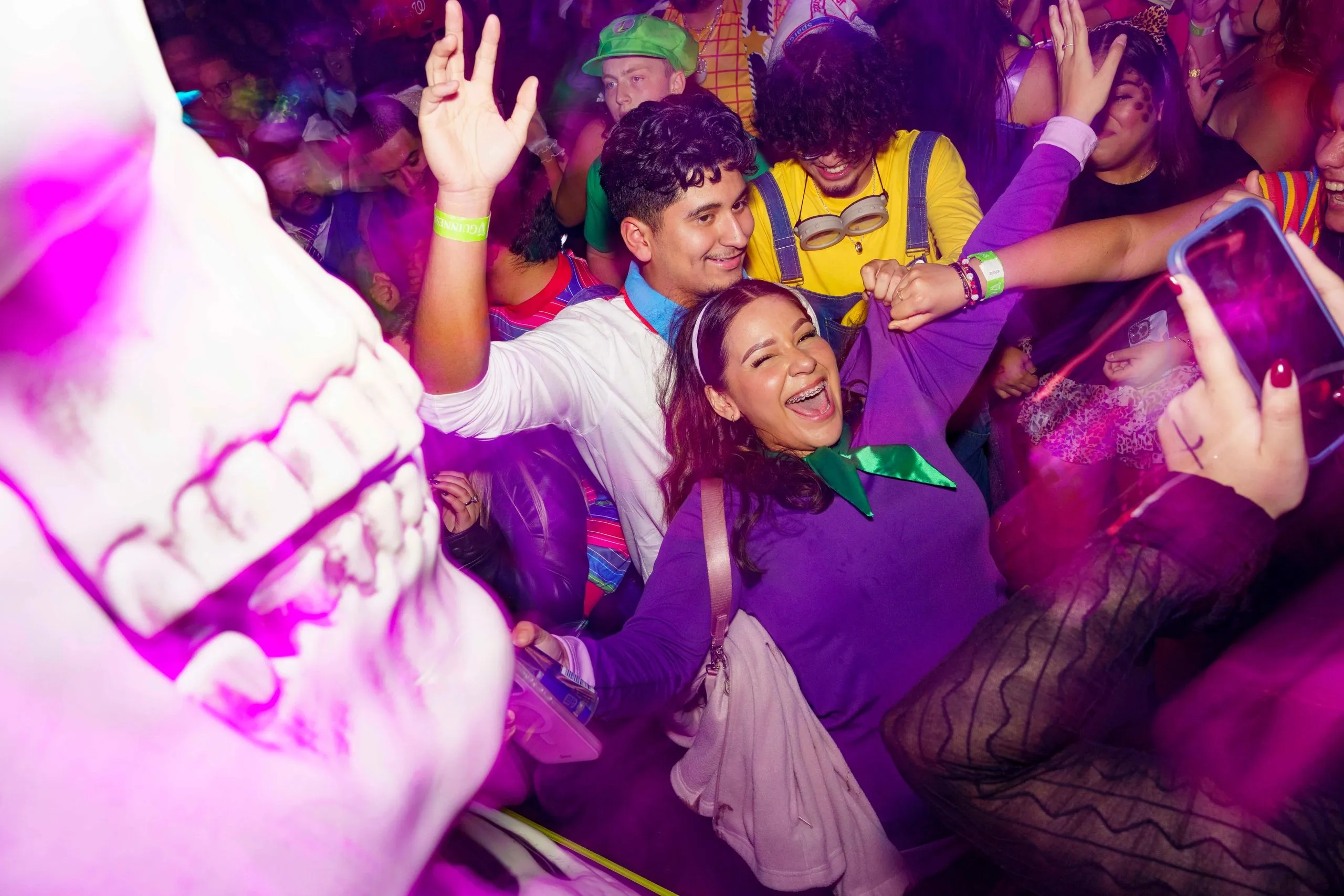 Two guests dancing beside a giant inflatable skull, the room washed in purple.