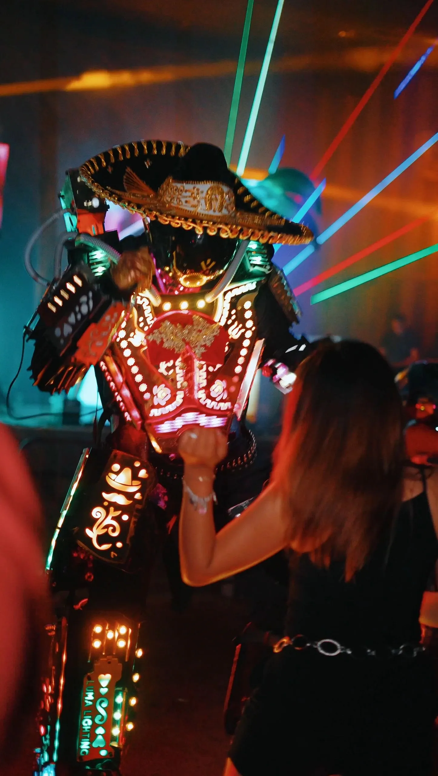 A performer in an LED-lit mariachi suit and sombrero moving through the crowd.