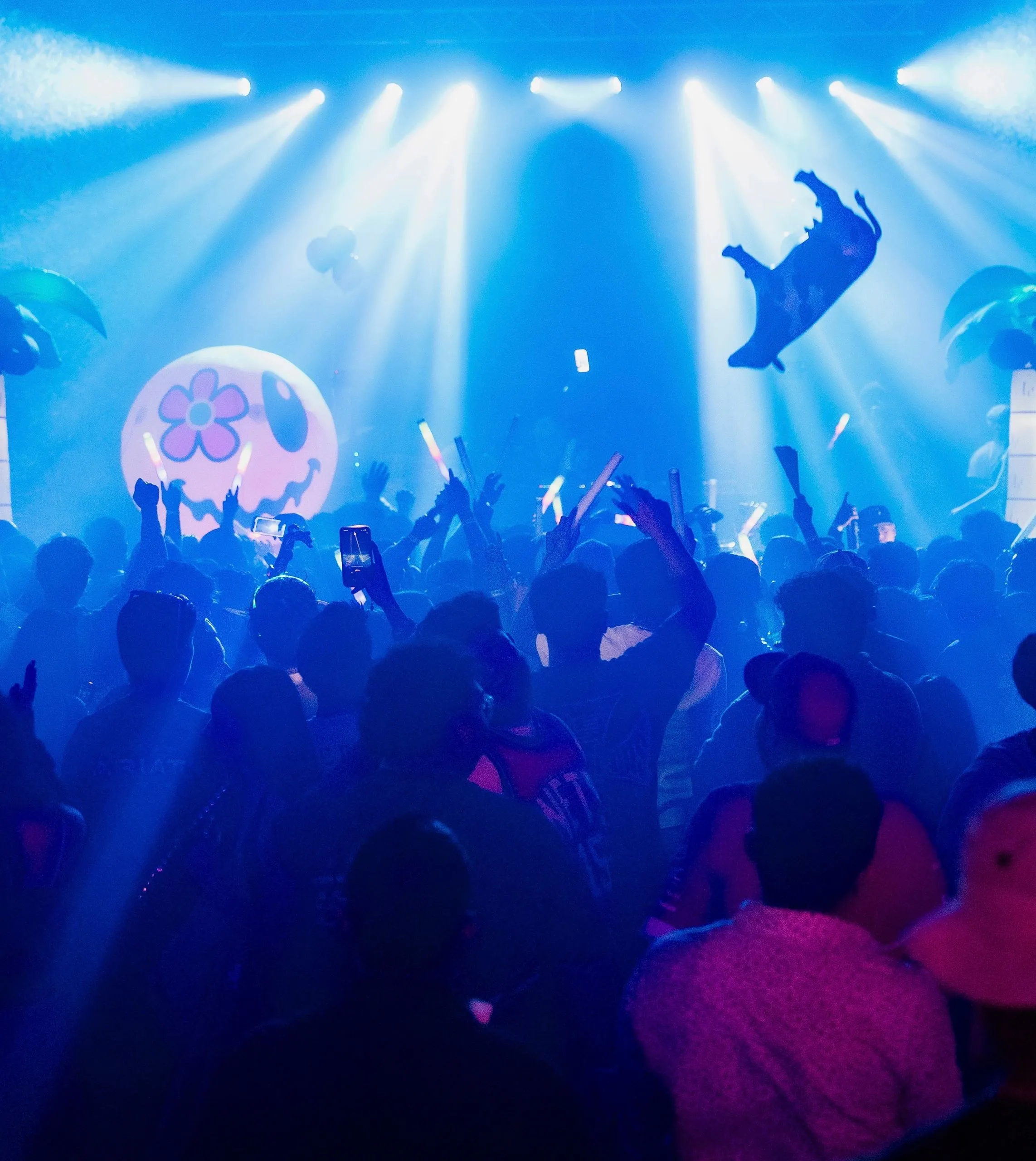 The floor under blue laser beams, with an inflatable smiley face and palm trees glowing at the back of the room.
